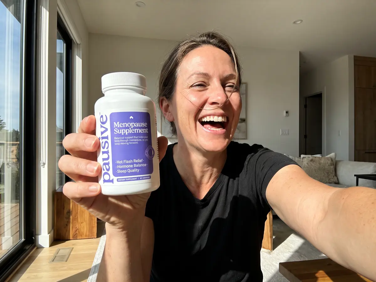 A woman laughing and holding a bottle of Pausive out toward the camera